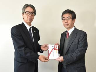 岡田学部長 (右) に目録を手渡す福富常務執行役